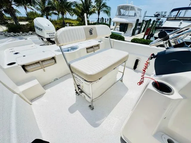 Slide: The Image of 2015 Carolina Skiff 198DLX boat interior with seating, Evinrude motor, and palm trees in background. - 9