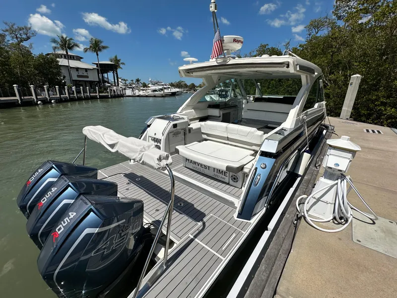 Slide: The Image of 2022 Formula 380 Super Sport Crossover boat docked, featuring triple outboard engines, under a clear blue sky. - 2