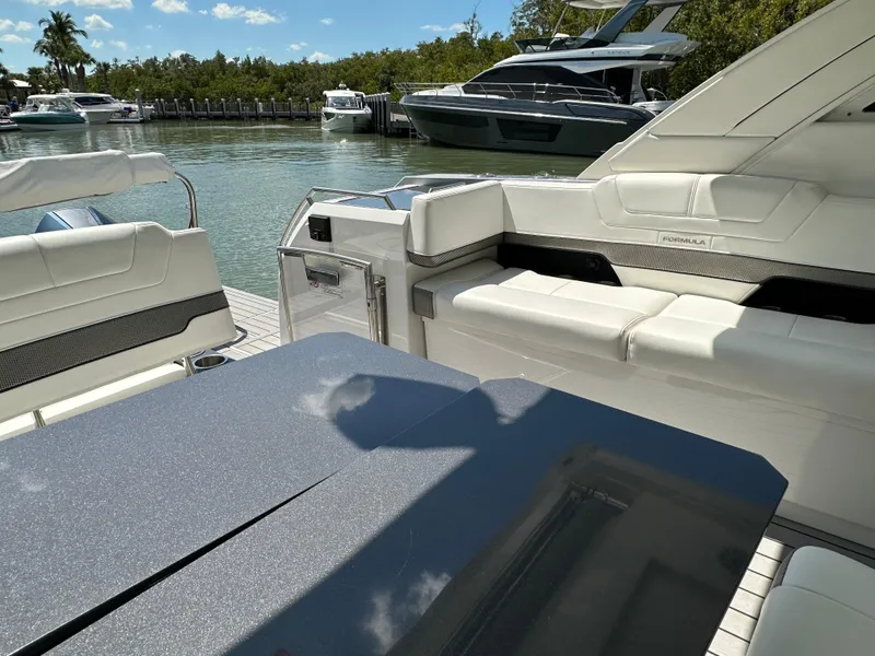 Slide: The Image of 2022 Formula 380 Super Sport Crossover boat interior with white seating, docked in a marina. - 29