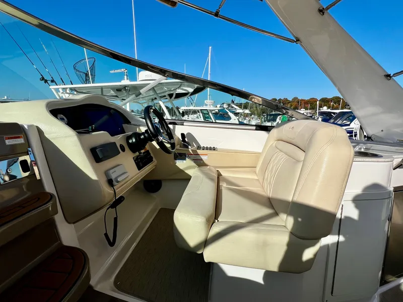 Slide: The Image of 2018 Regal 33 Express boat cockpit with beige seating and steering wheel, docked at marina. - 20