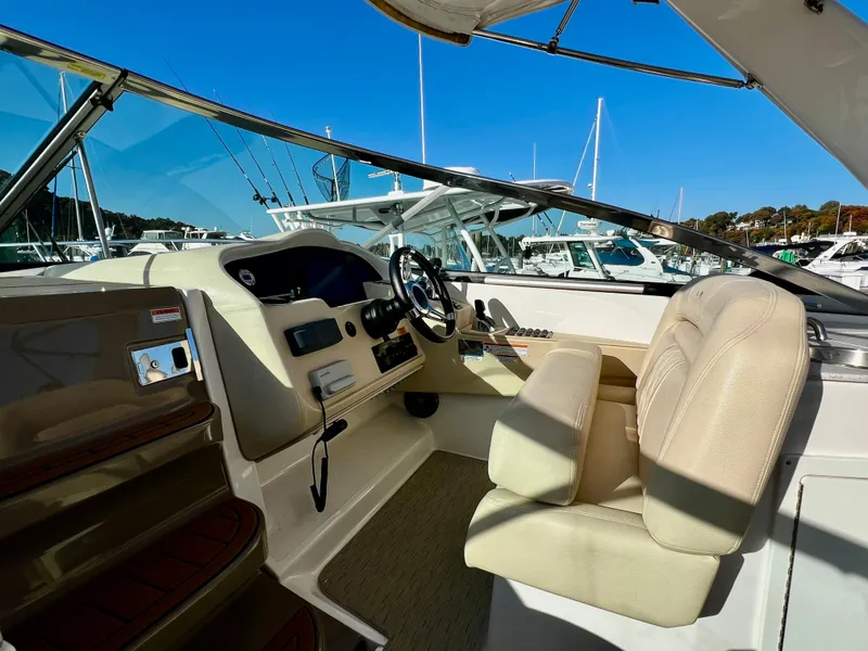 Slide: The Image of 2018 Regal 33 Express boat cockpit with steering wheel and beige seating. - 21
