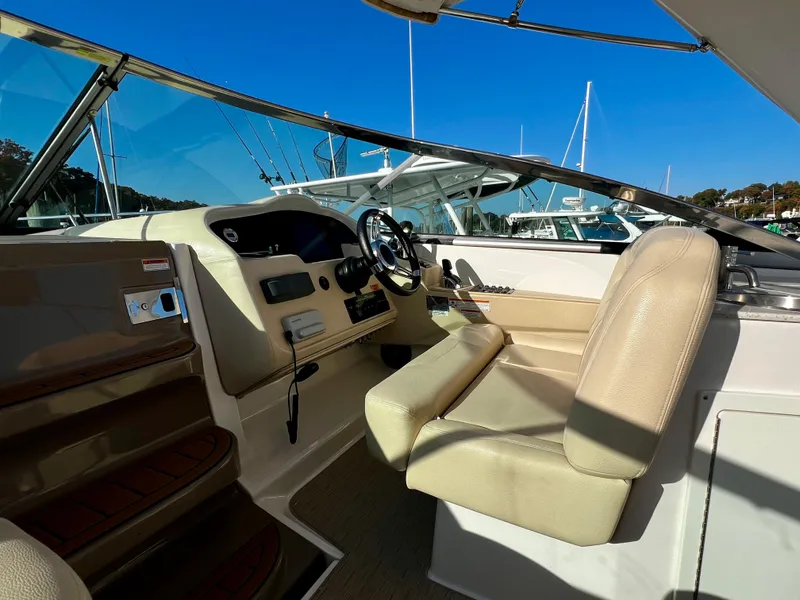 Slide: The Image of 2018 Regal 33 Express boat cockpit with beige seating and steering wheel, docked under clear blue sky. - 22