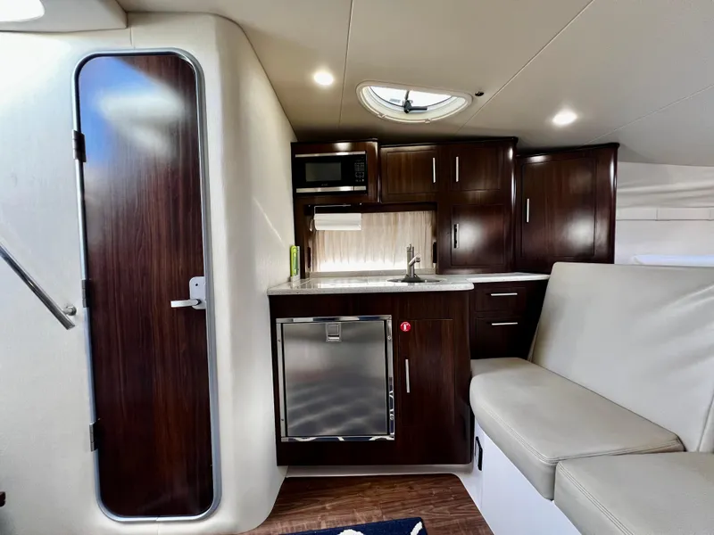 Slide: The Image of 2018 Regal 33 Express cabin interior with kitchenette, dark wood cabinets, and seating area. - 34