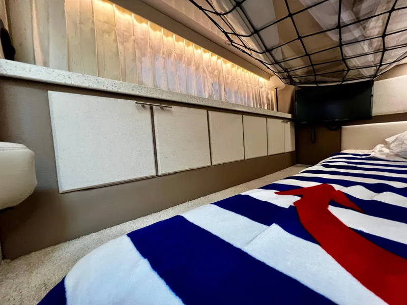 Slide: The Image of Interior of 2018 Regal 33 Express boat with striped bedding and modern cabinetry. - 8