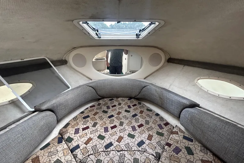 Slide: The Image of Interior cabin of a 2001 Sea Ray 245 Weekender boat, featuring cushioned seating and portholes. - 14