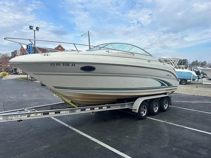 Slide: The Image of 2001 Sea Ray 245 Weekender boat on a trailer in a parking lot. - 2