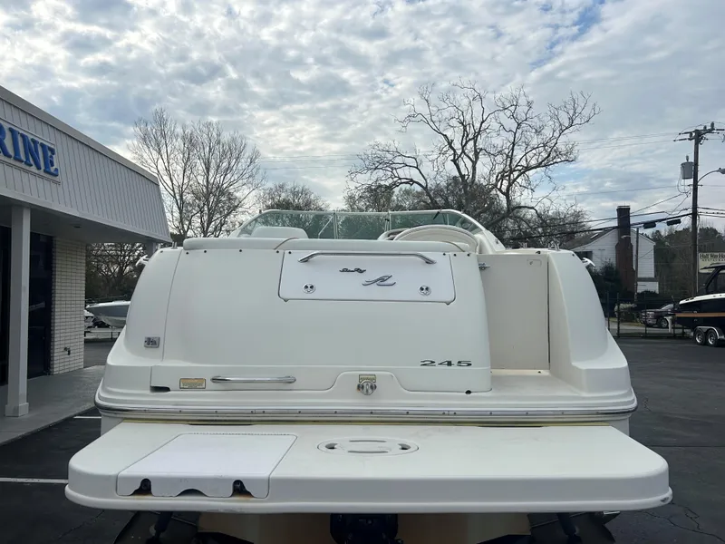 Slide: The Image of 2001 Sea Ray 245 Weekender boat, rear view, parked outdoors under cloudy sky. - 3
