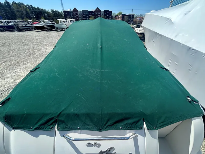 Slide: The Image of 2001 Sea Ray 245 Weekender boat with green cover in storage yard. - 9
