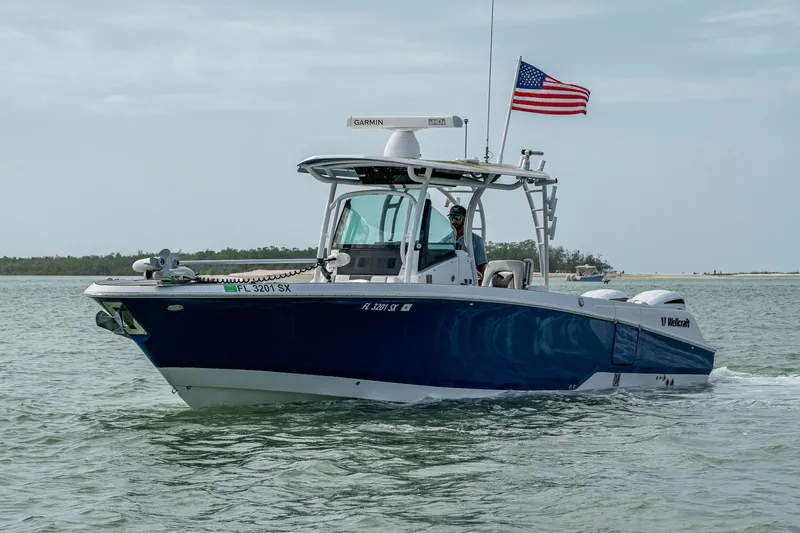The Image of 2020 Wellcraft 302 Fisherman boat cruising with American flag on open water. - 0