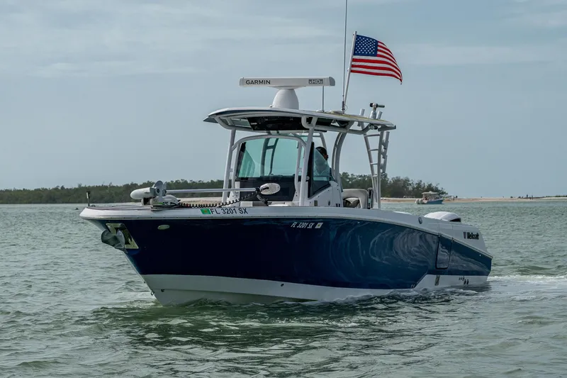 Slide: The Image of 2020 Wellcraft 302 Fisherman boat cruising with American flag on open water. - 1
