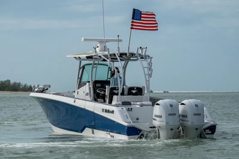 Slide: The Image of 2020 Wellcraft 302 Fisherman boat with dual Yamaha engines, American flag, cruising on water. - 10