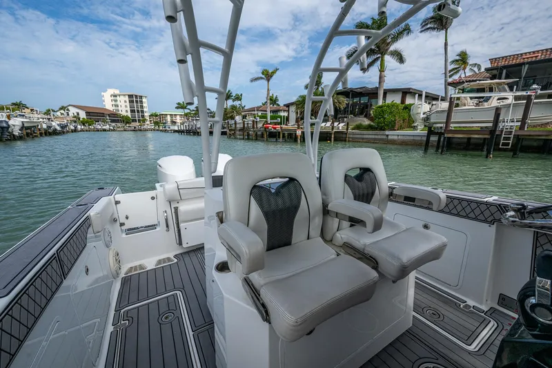 Slide: The Image of 2020 Wellcraft 302 Fisherman boat interior with dual seats, docked in a scenic marina. - 25