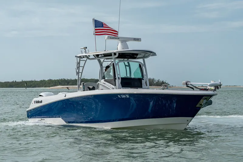 Slide: The Image of 2020 Wellcraft 302 Fisherman boat cruising on water with American flag. - 4