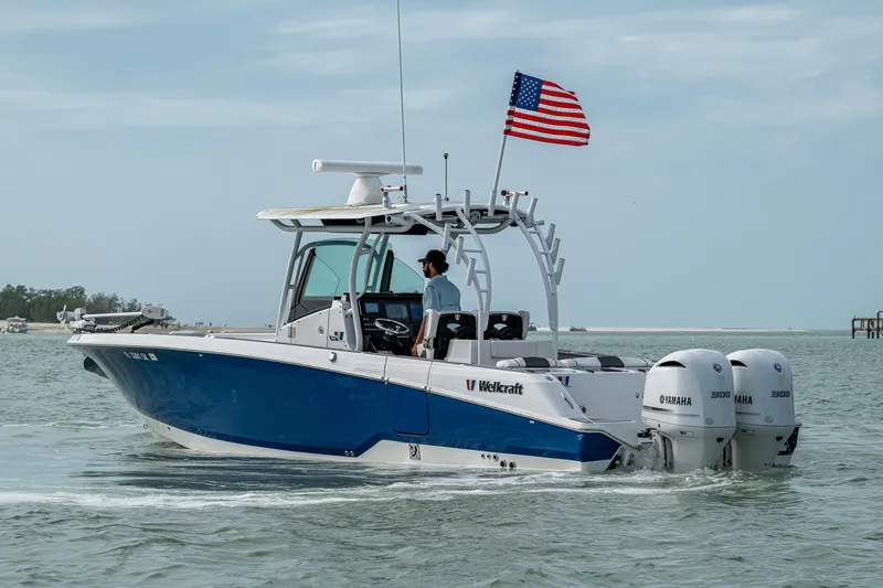 Slide: The Image of 2020 Wellcraft 302 Fisherman boat with dual engines and American flag on open water. - 47
