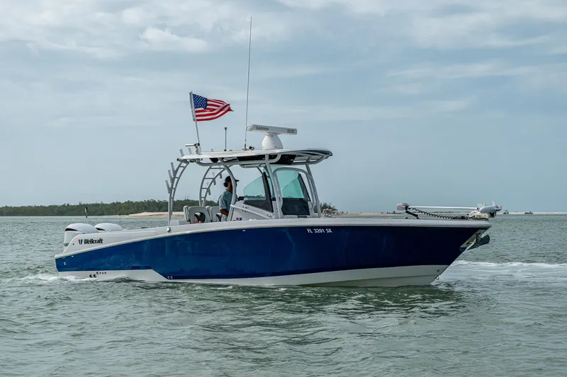 Slide: The Image of 2020 Wellcraft 302 Fisherman boat cruising on water with American flag. - 5
