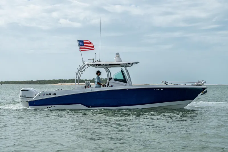 Slide: The Image of 2020 Wellcraft 302 Fisherman boat cruising with American flag on calm waters. - 6