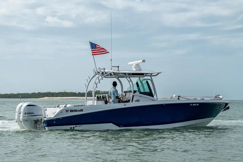 Slide: The Image of 2020 Wellcraft 302 Fisherman boat cruising on water with American flag. - 7