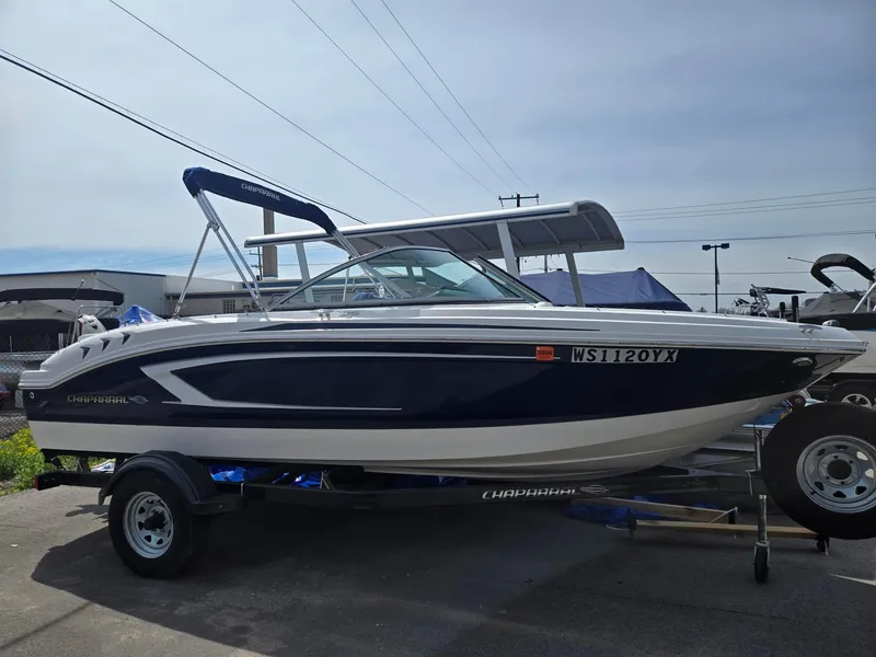 Slide: The Image of 2017 Chaparral 19H20 boat on trailer, blue and white design, parked outdoors. - 2