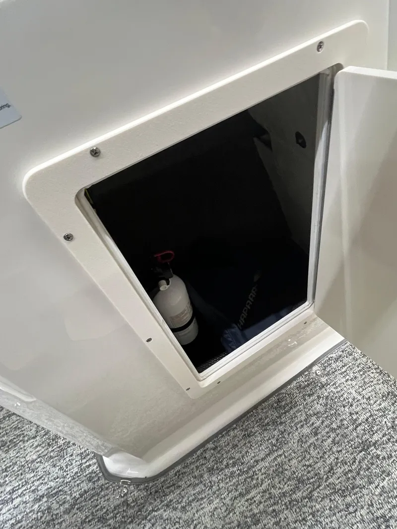 Slide: The Image of Open storage compartment in 2017 Chaparral 19H20 boat, showing interior and fire extinguisher. - 20