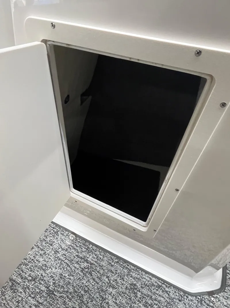 Slide: The Image of Open storage compartment on a 2017 Chaparral 19H20 boat, featuring a carpeted interior. - 21