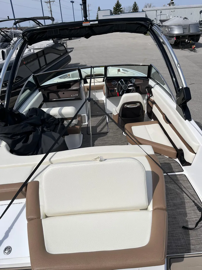 Slide: The Image of 2022 Cobalt CS23 boat interior with beige and white seating, docked outdoors. - 8