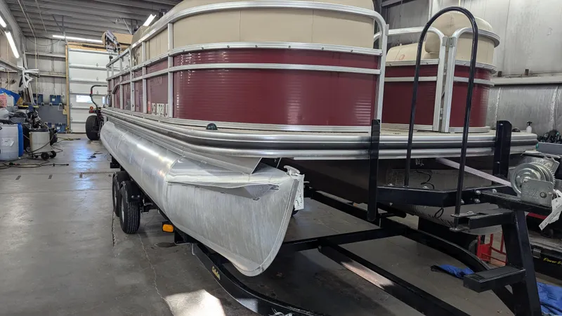 Slide: The Image of 2014 Lowe 2183 pontoon boat in a workshop, showing front damage. - 1