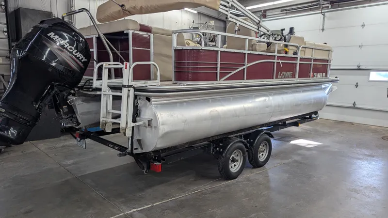 Slide: The Image of 2014 Lowe 2183 pontoon boat on trailer in garage with Mercury outboard motor. - 3