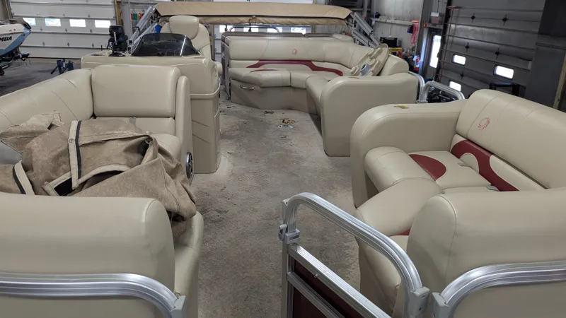 Slide: The Image of 2014 Lowe 2183 pontoon boat interior with beige seating in a garage setting. - 5