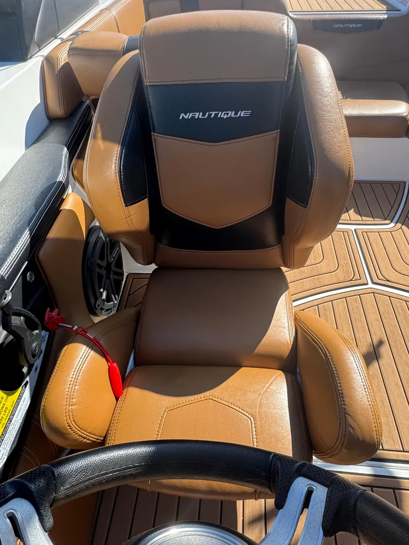 Slide: The Image of 2016 Nautique 210 boat interior with tan leather seating and steering wheel. - 11