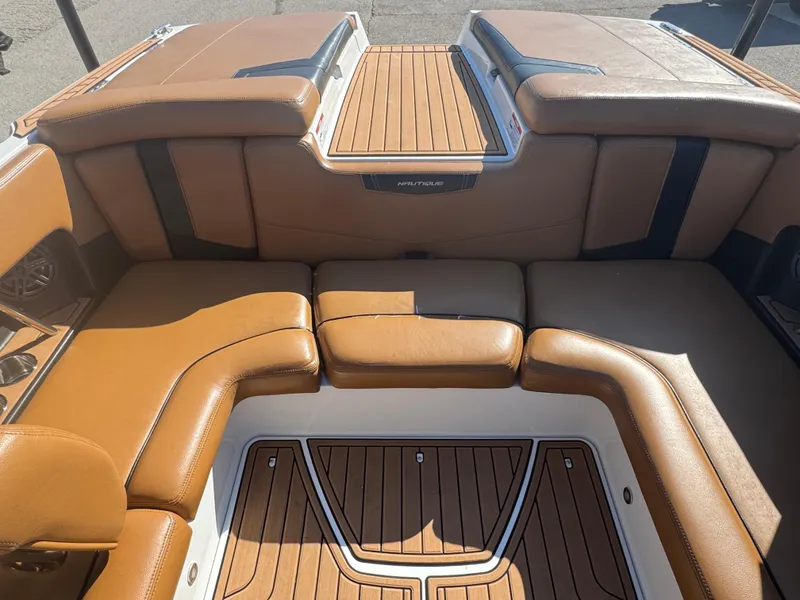 Slide: The Image of 2016 Nautique 210 boat interior with tan leather seating and teak flooring. - 12