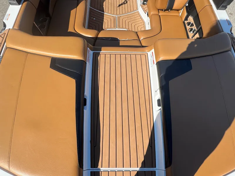 Slide: The Image of 2016 Nautique 210 boat interior with tan leather seats and wood-style flooring. - 20