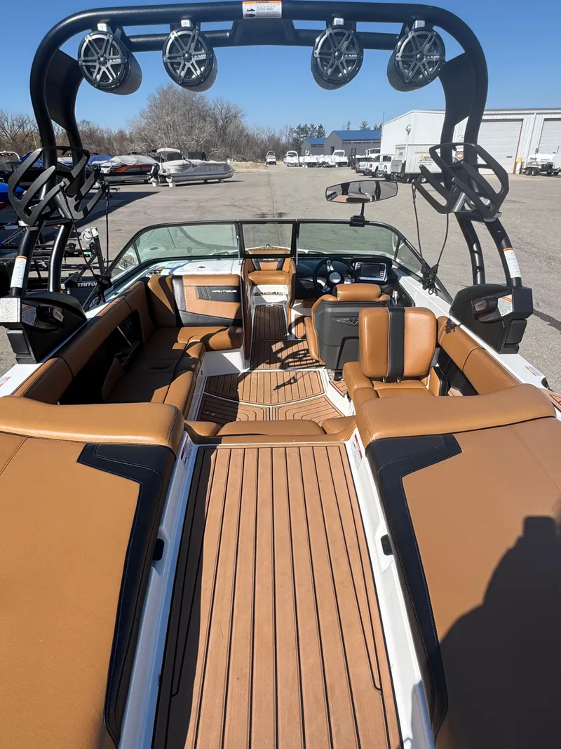 Slide: The Image of 2016 Nautique 210 boat interior with tan seating and black tower speakers. - 22