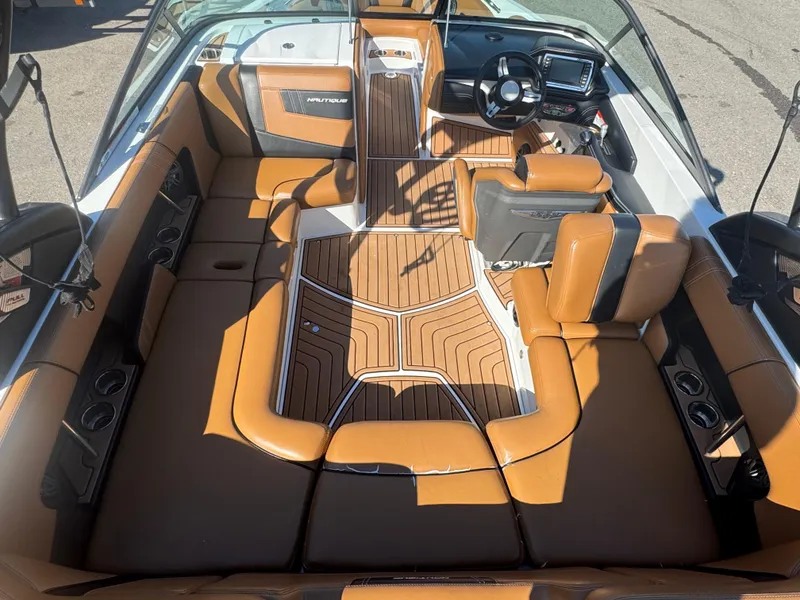 Slide: The Image of 2016 Nautique 210 boat interior with tan leather seats and modern dashboard. - 23