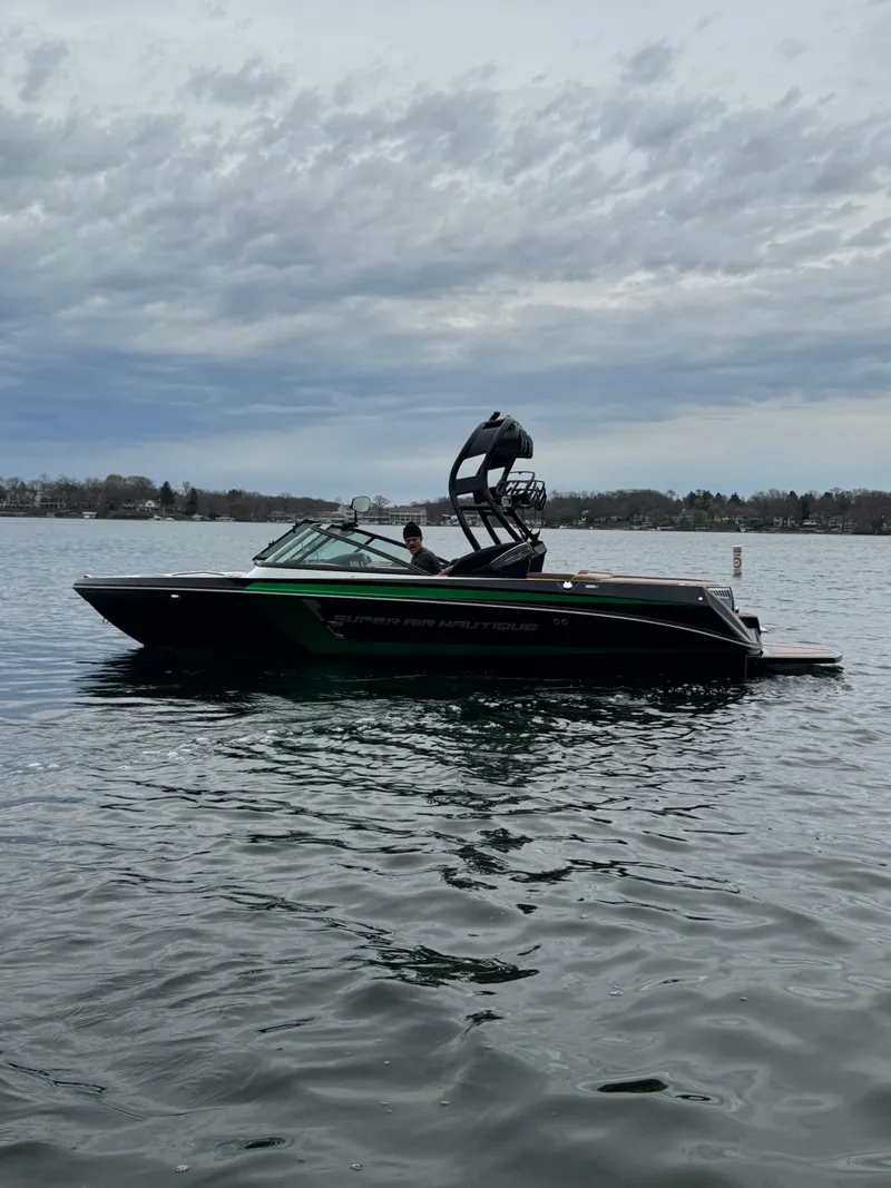 Slide: The Image of 2016 Nautique 210 boat on a calm lake under cloudy skies. - 3