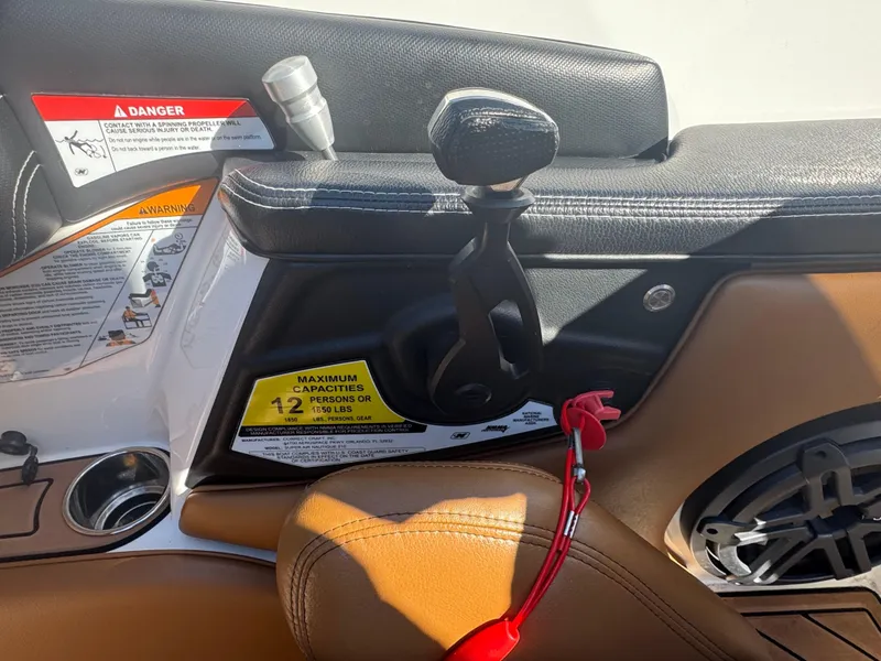 Slide: The Image of 2016 Nautique 210 boat interior with throttle control, warning labels, and cup holder. - 30
