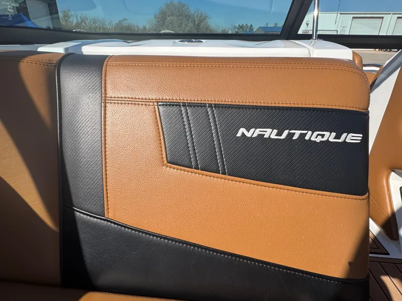 Slide: The Image of 2016 Nautique 210 boat interior with brown and black leather seating. - 36
