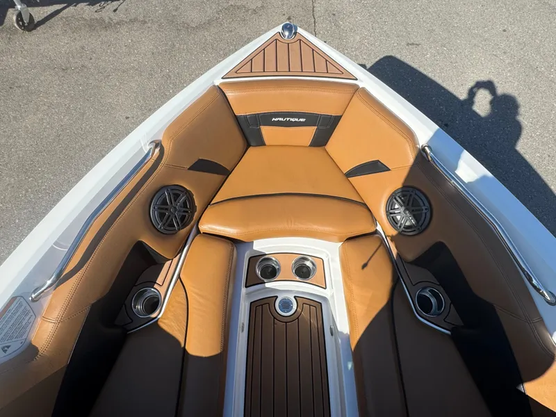 Slide: The Image of 2016 Nautique 210 boat interior with tan leather seats and built-in speakers. - 38