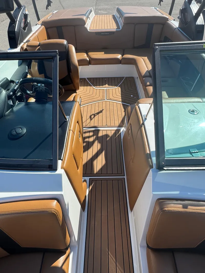 Slide: The Image of 2016 Nautique 210 boat interior with tan leather seats and wood-style flooring. - 8