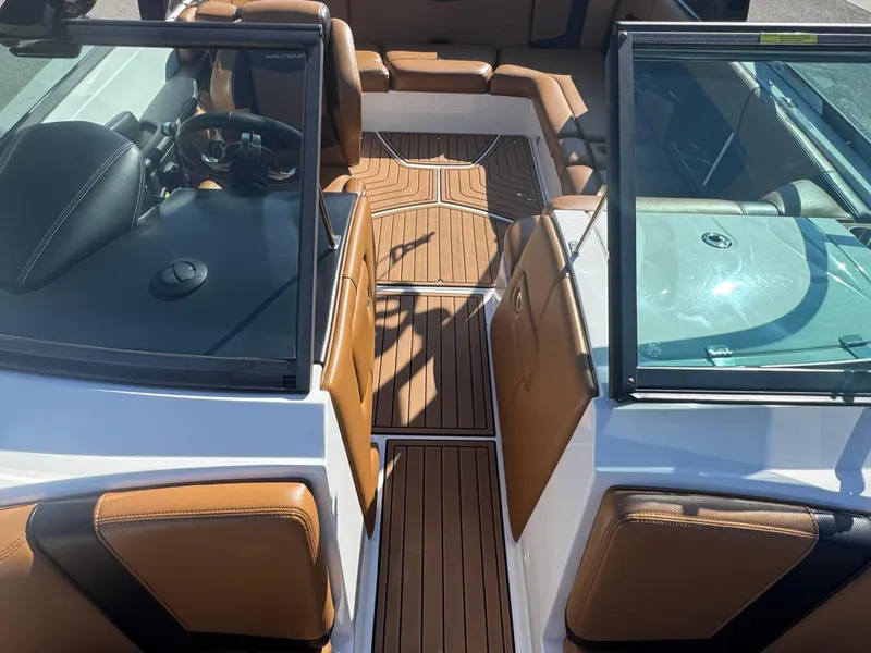 Slide: The Image of 2016 Nautique 210 boat interior with brown leather seats and wooden flooring. - 9