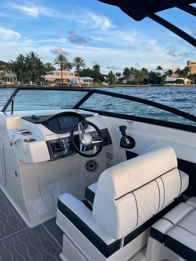 Slide: The Image of 2015 Sea Ray 290 Sundeck boat interior with steering wheel, white seating, and waterfront view. - 23