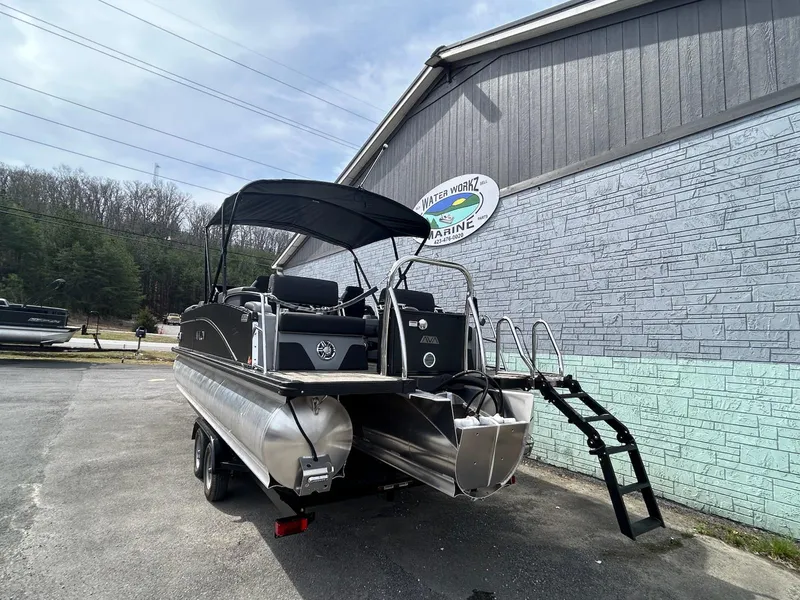 Slide: The Image of 2025 Avalon 2585 Catalina Quad Lounger boat with windshield, parked outside a marine shop. - 4