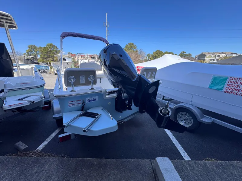 Slide: The Image of 2025 Boston Whaler 170 Montauk boat with outboard motor, parked in a marina. - 2