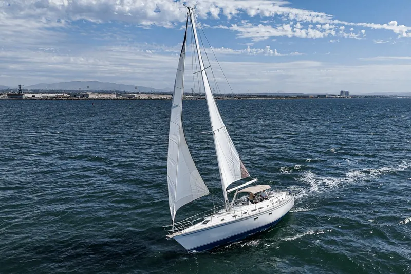 Slide: The Image of Sailboat Morgan 45 Catalina 1992 cruising on ocean with naval ships in background. - 22