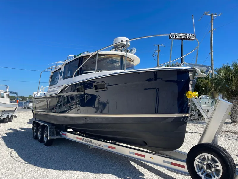 Slide: The Image of 2022 Ranger Tugs R-27 boat on trailer, parked outdoors under clear blue sky. - 1