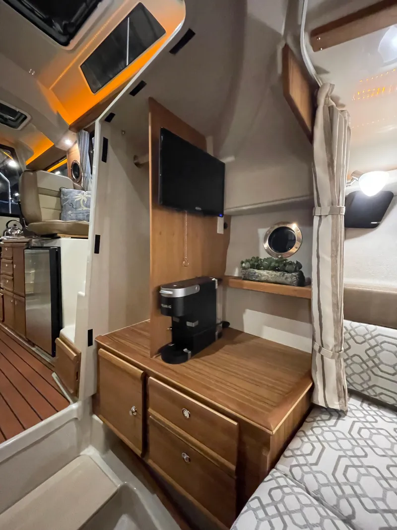 Slide: The Image of Interior of 2022 Ranger Tugs R-27 with TV, coffee maker, and cozy seating area. - 16