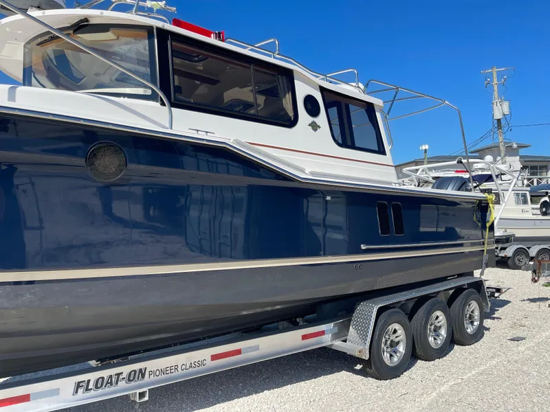 Slide: The Image of 2022 Ranger Tugs R-27 boat on trailer, side view, blue and white exterior. - 2