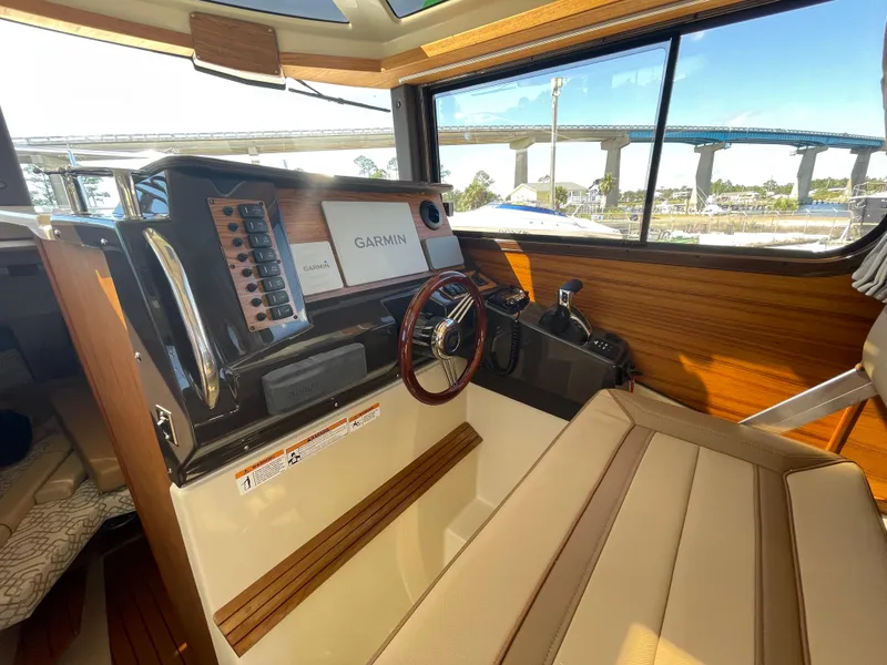 Slide: The Image of 2022 Ranger Tugs R-27 helm with Garmin navigation, wood accents, and bridge view. - 8