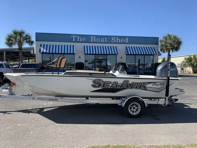 Slide: The Image of 2025 SeaArk Easy 200 boat on trailer outside The Boat Shed with blue-striped awnings. - 0