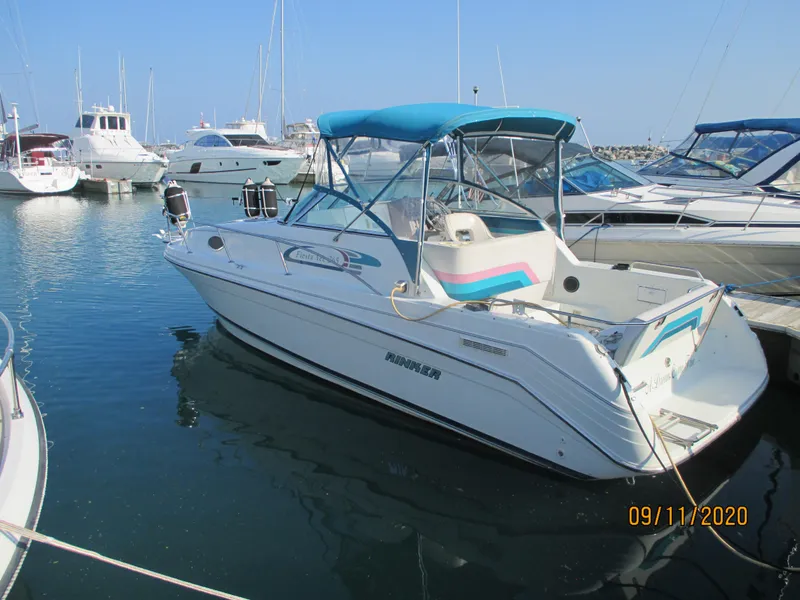 The Image of 1994 Rinker Fiesta Vee 265 boat docked in marina, featuring blue canopy and white hull. - 1