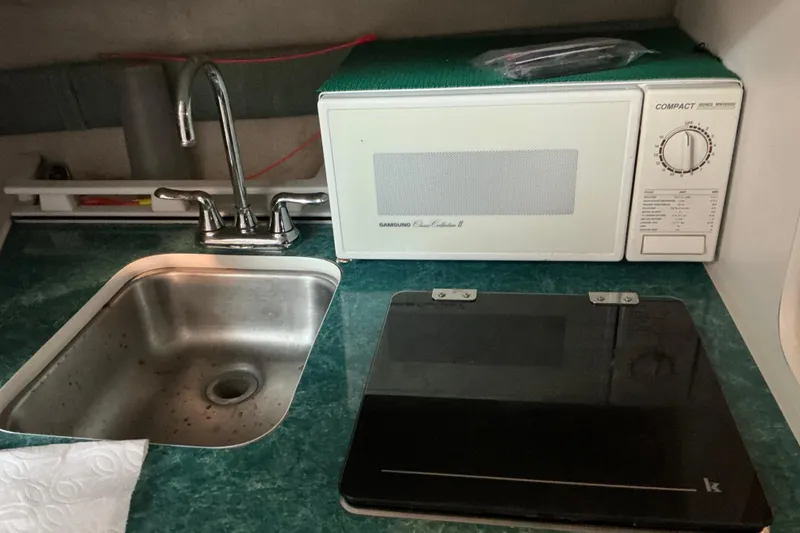 Slide: The Image of 1994 Rinker Fiesta Vee 265 kitchenette with sink, microwave, and stovetop. - 42